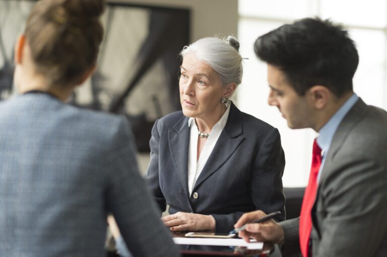 Three business professionals engaged in a discussion in a modern office setting.