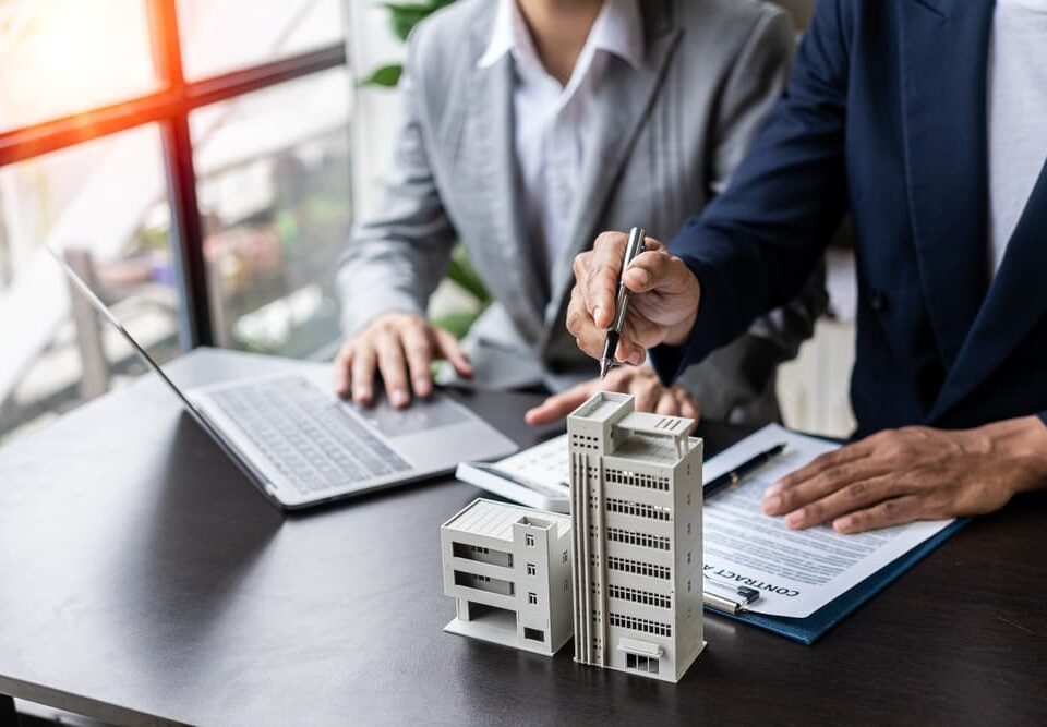 Businessman holding model small building house with property