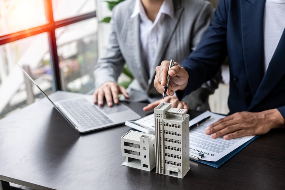 Businessman holding model small building house with property