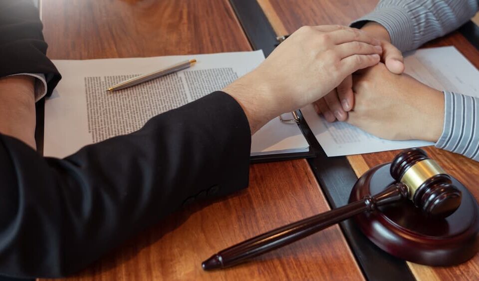 Lawyer working with client discussing probate papers with brass scale about legal legislation in courtroom