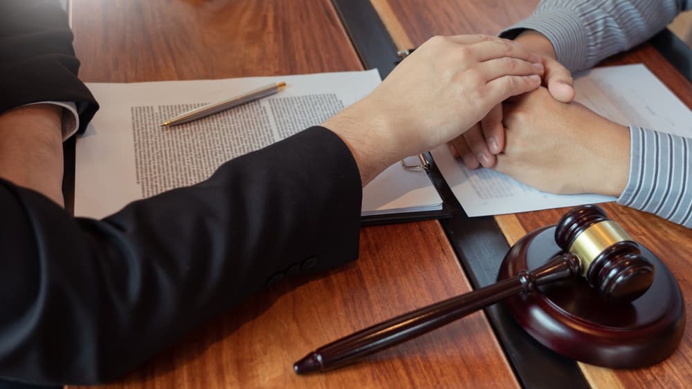 Lawyer working with client discussing probate papers with brass scale about legal legislation in courtroom