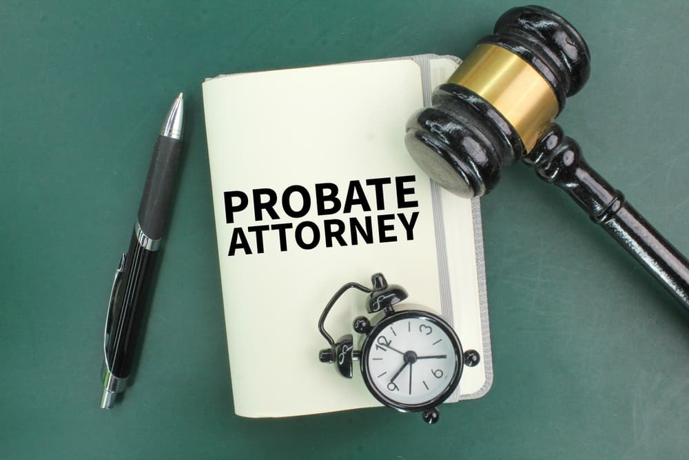 A pen, a judge's gavel, an alarm clock and a book with the words probate attorney.