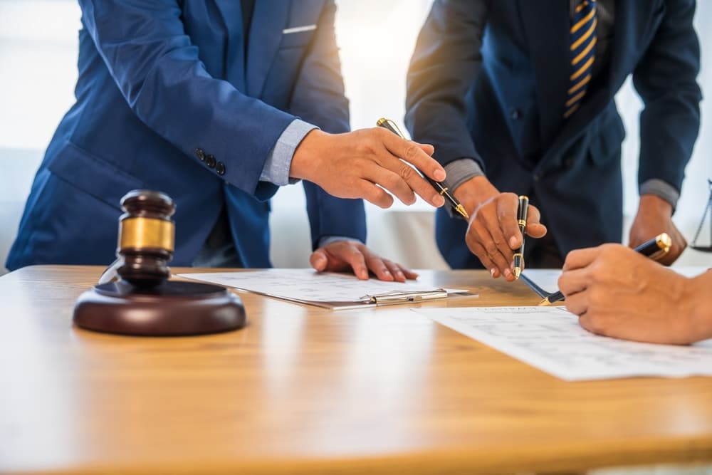A team meeting of probate lawyer in formal suits is taking place at a desk, discussing a various aspects of debt in probate