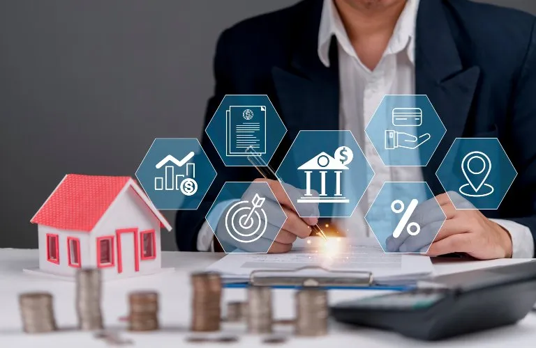Person in business attire signing a document with a model house, stacked coins, and financial icons overlay.