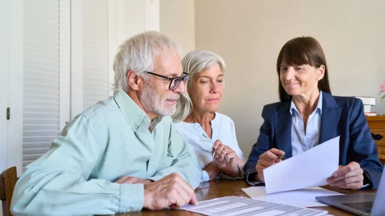 Three adults, two seniors and a professional woman, reviewing documents at a table.