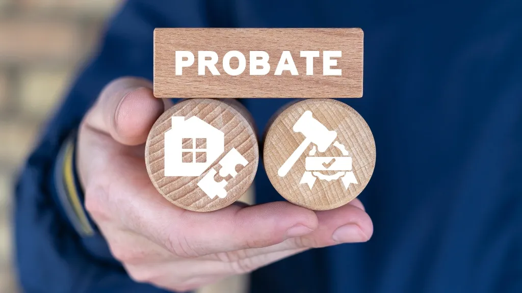 Hand holding wooden blocks with "PROBATE" text and icons of a house puzzle and a judge's gavel.